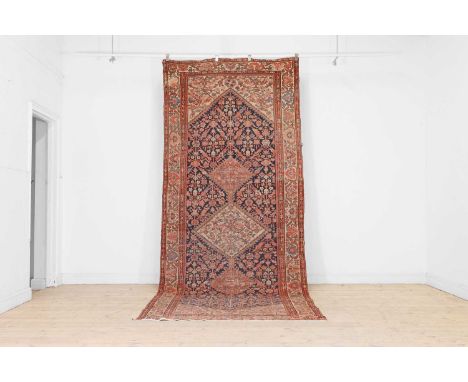 A Persian tribal wool runner, early 20th century, the indigo and ivory fields with a triple-medallioned centre, enclosed by f