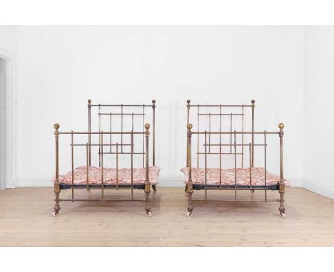 A pair of Victorian brass single beds, mid-19th century, each tubular frame raised on porcelain castors, and each with linen 