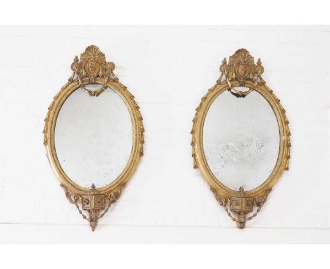 A pair of carved giltwood and gesso girandole mirrors,  second half of the 18th century, each oval plate within a moulded fra