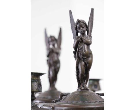 A pair of bronze two-light candelabra, late 19th/early 20th century, each surmounted by a winged figure above foliate cast de