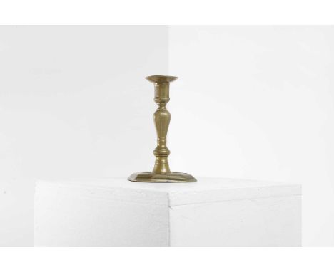 A brass candlestick, 18th century, French, the circular drip pan above a faceted knopped stem, on an octagonal base, 10.5cm d