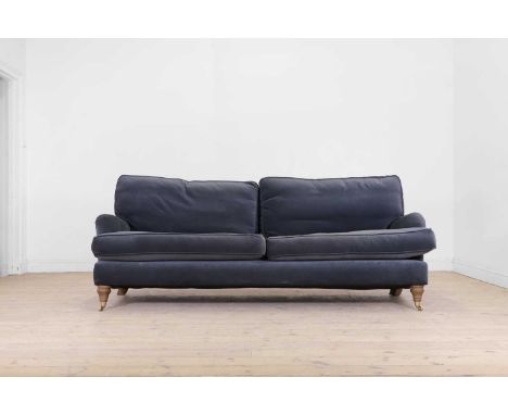 A two-seater sofa in the Howard & Sons style, of recent manufacture, raised on turned supports, terminating in brass caps and