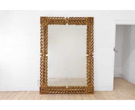 A large Regency-style carved giltwood mirror, of recent manufacture, with a bold foliate frame surrounding a rectangular glas