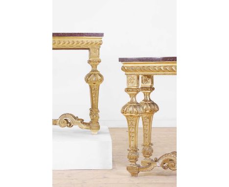 A pair of Louis XIV-style giltwood console tables, late 19th century, French, each with a porphyry top above a gadrooned frie