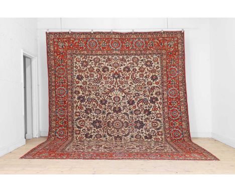 A Persian wool carpet, 20th century, Kashan, the pale field woven with scrolling Shah Abbasi motifs within a wide red-ground 