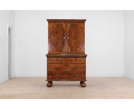 A walnut cabinet on chest, early 18th century and later, with a cavetto cornice above a pair of doors enclosing a fitted inte