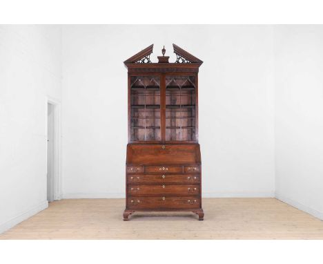 A George III mahogany bureau bookcase, third quarter of the 18th century and later, with a broken pediment above a pair of gl