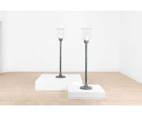 A pair of patinated bronze storm lantern stands, 20th century, each with a glass shade above a tubular column and spreading c