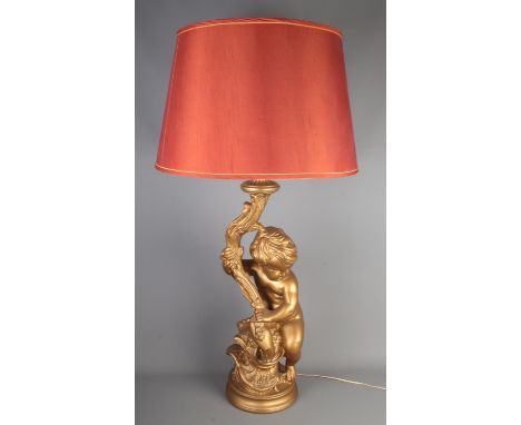 A large gilt lamp formed as a seated putto, with shade. Height to fitting 69cm.
