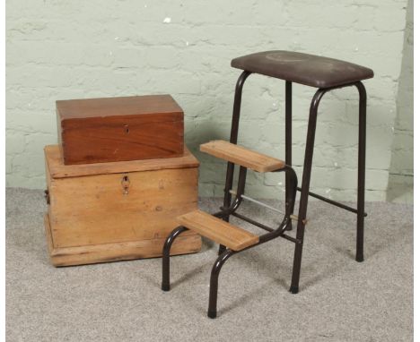 A folding step stool along with two antique boxes.