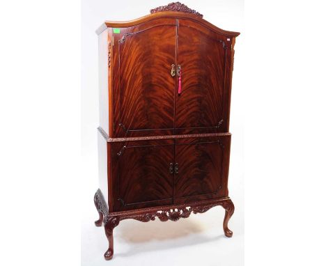 A 20th Century walnut Queen Anne revival cocktail cabinet. The cabinet raised on carved cabriole legs having lower square doo