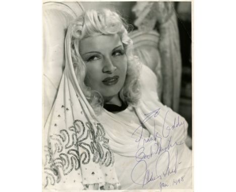 WEST MAE: (1893-1980) American actress and sex symbol. Vintage signed and inscribed 8 x 10 photograph of West seated in a hea