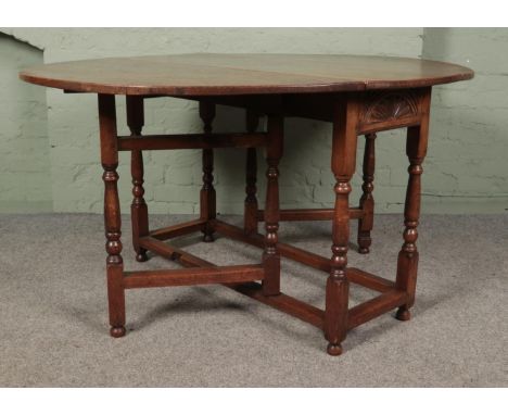 An oak drop leaf gate leg table featuring carved sun burst motif to ends. Approx. dimensions with leaves dropped 122cm x 47cm
