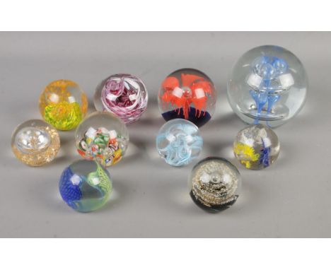 A collection of ten paperweights of varying sizes to include Caithness Weaver 2005 and examples featuring bubble inclusions. 