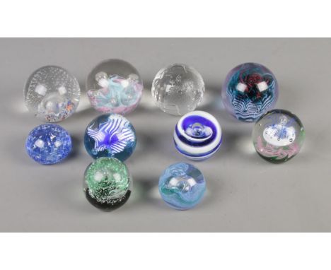 A collection of ten glass paperweights to include Milliennium globe, Caithness and Selkirk glass examples.  
