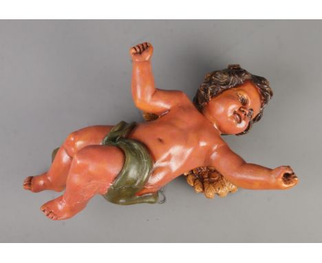 A large painted plaster wall hanging model of a cherub. Approx. length 53cm.  Possibly missing bugle. Wings loose.