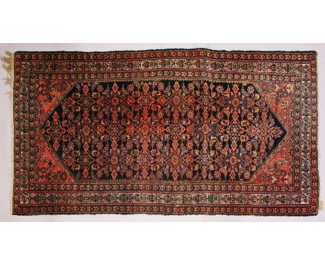 A PERSIAN CARPET, dark blue ground with stylized floral decoration. 290cms x 155cms.