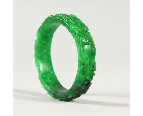 A CHINESE CARVED GREEN JADE BANGLE. 7.5cms diameter.