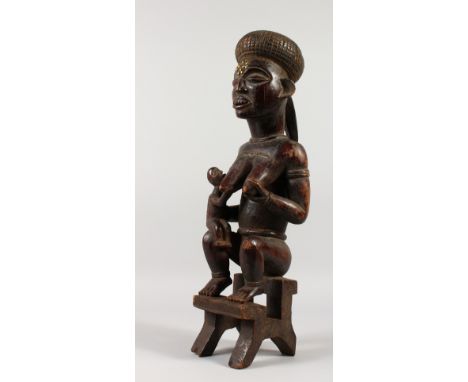 A GABON CARVED WOOD TRIBAL FERTILITY FIGURE from the Kota Tribe, mother and child sitting on a stool. 52cms high.