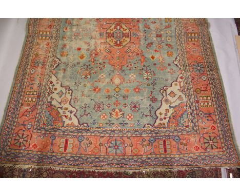 A LARGE HERIZ CARPET, pale blue ground, salmon pink central motif in a confirming border (worn). 4.3m x 3.5m.