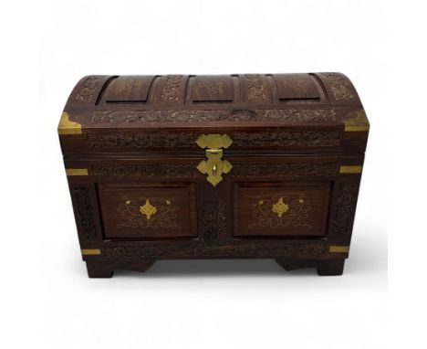 Indian hardwood dome top travelling trunk, profusely carved with foliate and geometric motifs, the panelled domed lid and fro