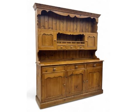 Traditional vintage pine kitchen dresser with scrolled cornice and rack with long shelf above a galleried shelf flanked by th