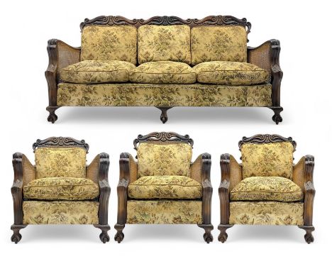 Three-seat rococo revival style stained beech settee, with blind scrollwork top rail and arms, cane sides and back, on ball a