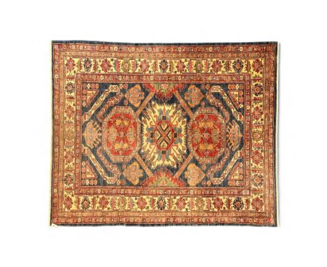 Persian Heriz carpet, the indigo field with bold central medallion in rust red and ivory, flanked by geometric floral forms a