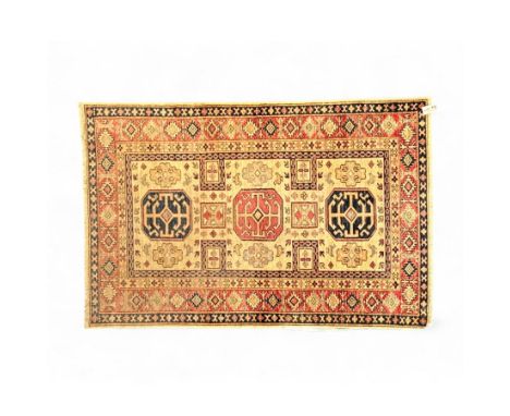 Afghan ivory and crimson ground rug with geometric decoration, the central field with three bold octagonal medallions in navy