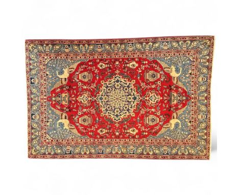 Central Persian Isfahan carpet, central ivory medallion with scrolling floral motifs on a ruby red field, flanked by pale blu