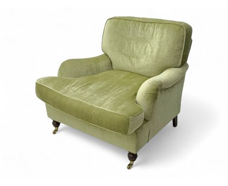 20th century Howard style armchair, upholstered in green velvet, deep cushioned back and seat with shaped arms, on short turn