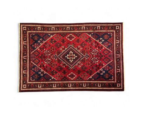 North West Persian Josheghan rug, the central dark blue diamond medallion within a stepped lozenge field of red with repeatin