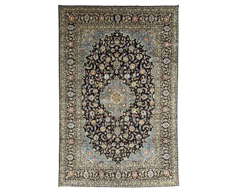 Persian Kashan indigo ground carpet, floral pattern light blue ground central medallion and spandrels, the fielding decorated