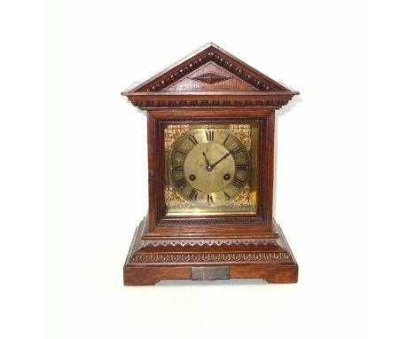 Late 19th Century German mantel clock, the gilt 15cm square dial with black Roman numerals and chapter ring, scroll spandrels