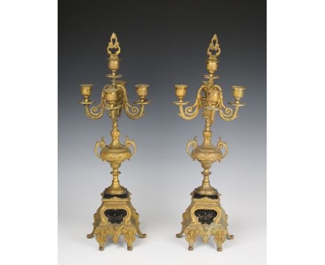 A pair of 19th century gilded spelter four branch candelabra with a fifth central sconce with snuffer, on a central urn mount