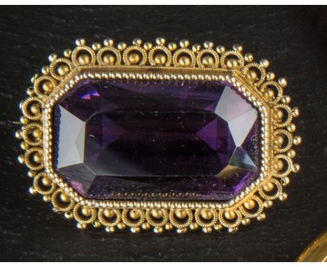 A Victorian yellow gold and amethyst brooch tests as 14ct, the 24 x 14mm. emerald cut amethyst within a beaded rim and bead a