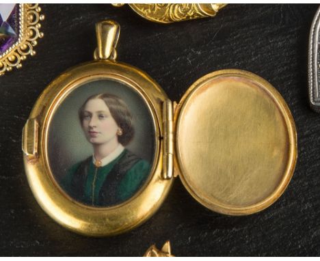 A Victorian yellow gold locket portrait miniature the domed oval locket with Gothic style hinge and latch, opening to reveal 