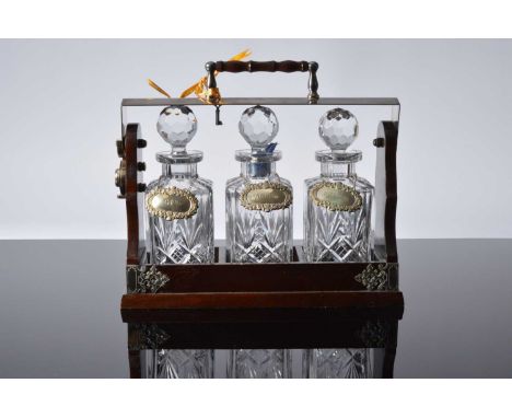 A c1960s or later tantalus from Mappin & Webb, the wooden and silver mounted lockable three glass decanter holder with key an