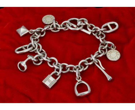 A Hermes silver charm bracelet,  with the seven icon charms related to the Hermes brand, with a bar and circle clasp 23 cm lo