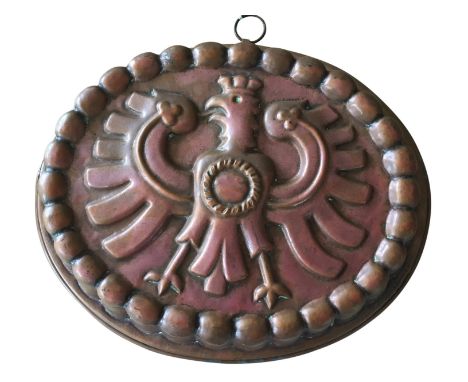A copper cake mould, early 20th century, with an eagle crest, fluted sides, with hanging ring, 35cm long
