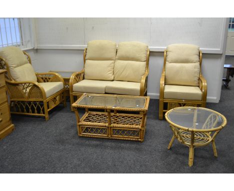 A wicker work conservatory suite comprising; two seater sofa, pair of arm chairs, coffee table, etc 