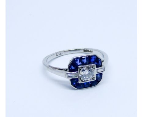 Art Deco sapphire and diamond ring set with a central brilliant cut diamond surrounded by princess cut sapphires in a square 