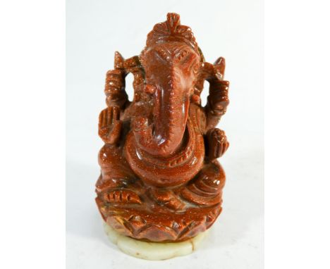 An Indian carved gold stone model of Ganesh on a soap stone disc style base height 11cms