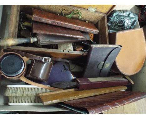 A box containing old shaving equipment, camera lense, leather purses, books, ornate ashtrays etc 