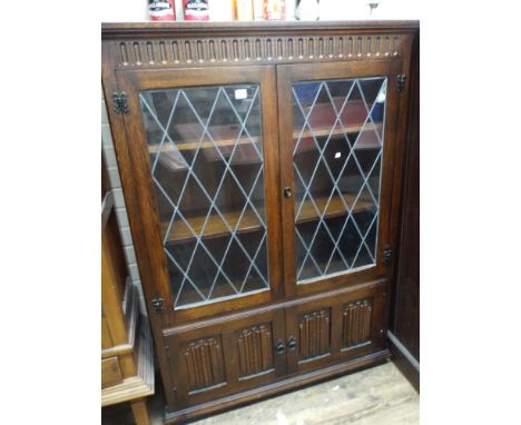 A dark oak linen fold carved panel leaded glazed bookcase 