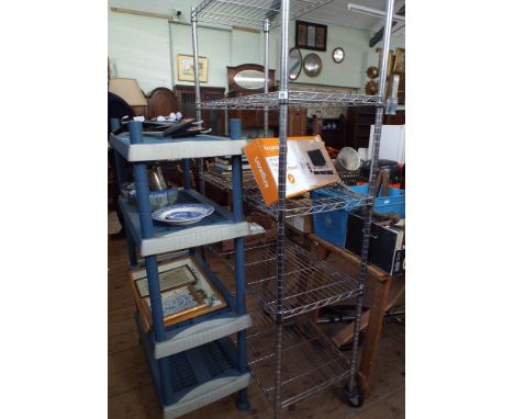 A metal five tier storage rack on wheels and another heavy plastic four shelf rack