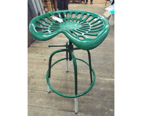 A cast iron adjustable tractor seat on stool base in green 
