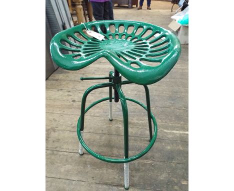 A cast iron adjustable tractor seat on stool base in green 