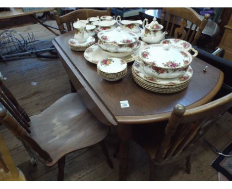 A circular oak drop leaf dining table and four similar stick back chairs 