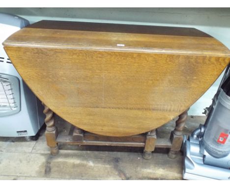 A 1930's oval oak gate leg dining table on barley twist legs 3'6 wide 